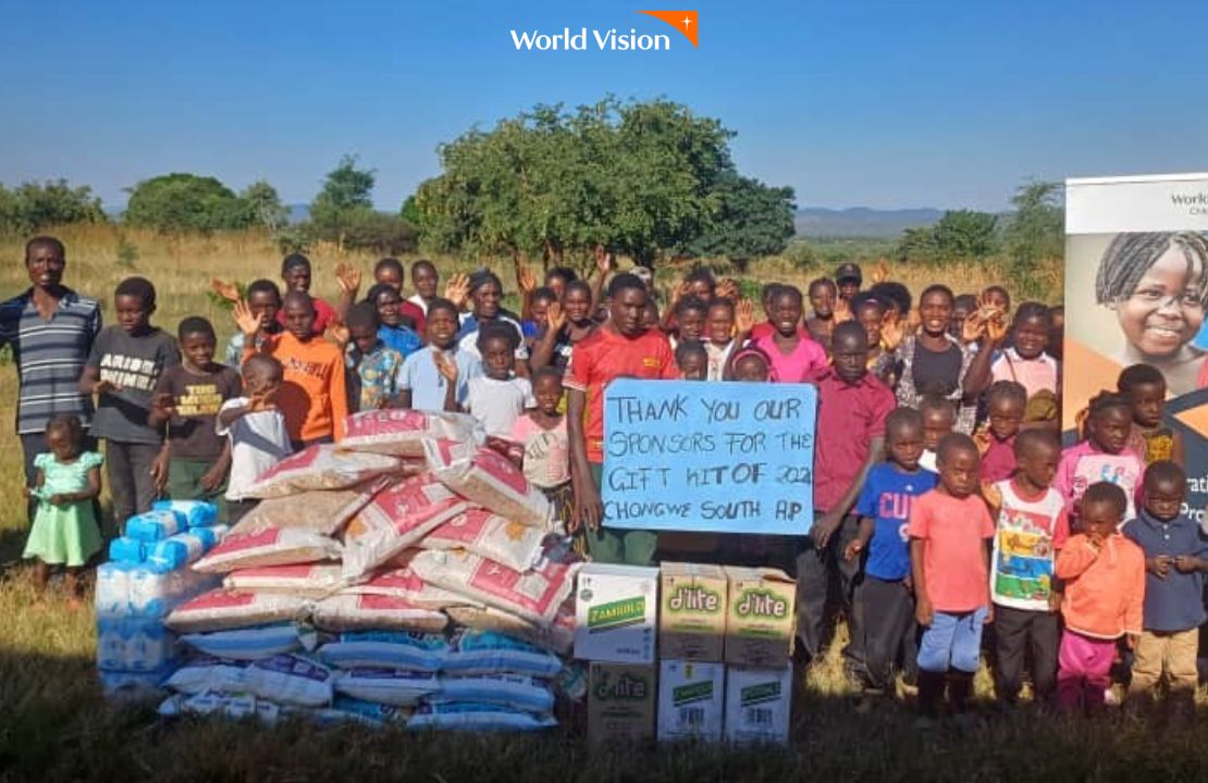 다양한 식료품을 선물받아 감사하다는 메세지를 들고 포즈를 취하는 잠비아 지역주민들과 아이들