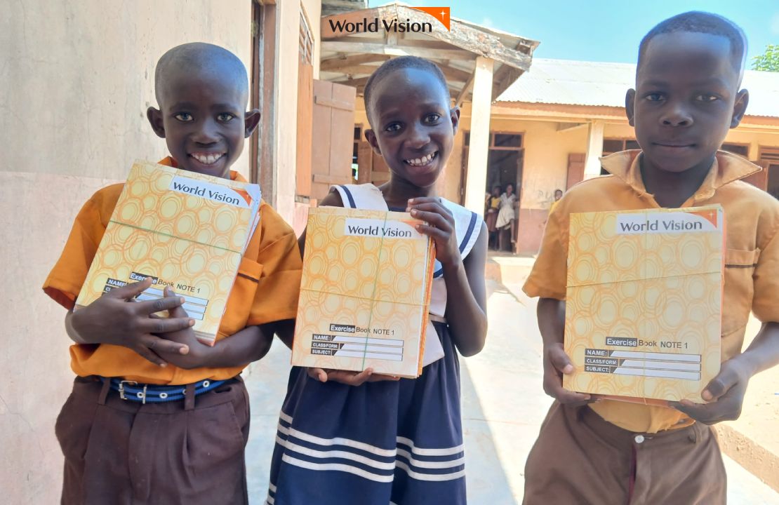 선물받은 공책을 들고 미소짓는 세명의 가나 아이들