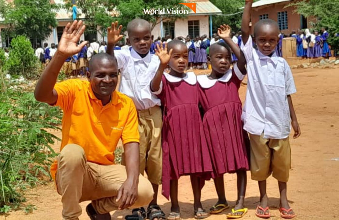 현지직원 옆에서 손 흔들고 있는 교복 입은 아이들