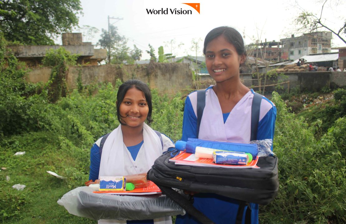 학용품더미를 보여주며 미소짓는 여자아이들