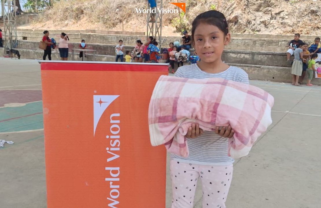 선물받은 이불을 품에 앉고 미소짓는 여자아이